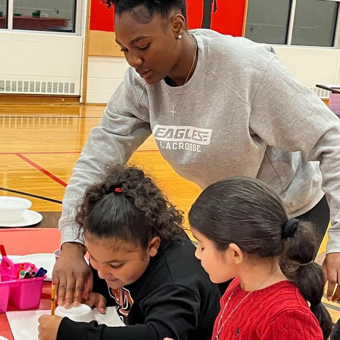 A teacher helping two students with a drawing craft.