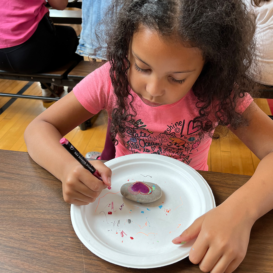 A girl engaging in a rock painting craft. 