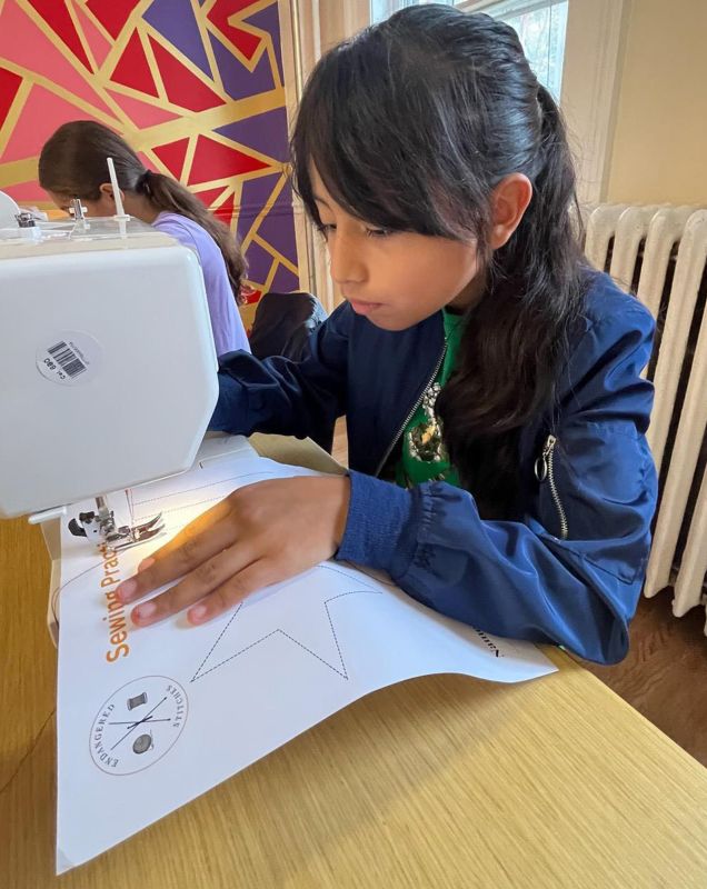 A girl focused while working at a sewing machine. 